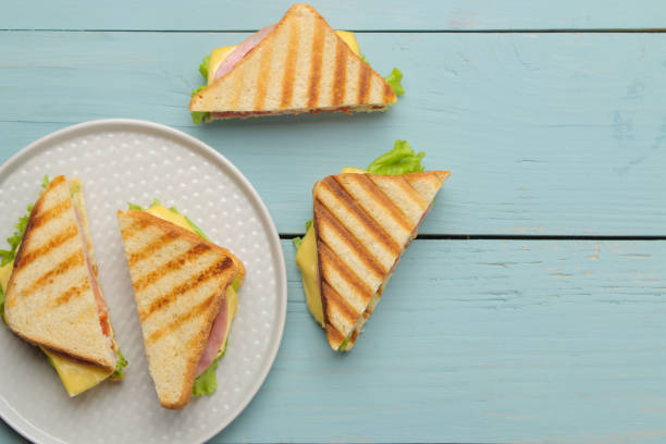 istock Sandwich on a plate with ham, cheese and tomato on a blue background. top view 1626177208