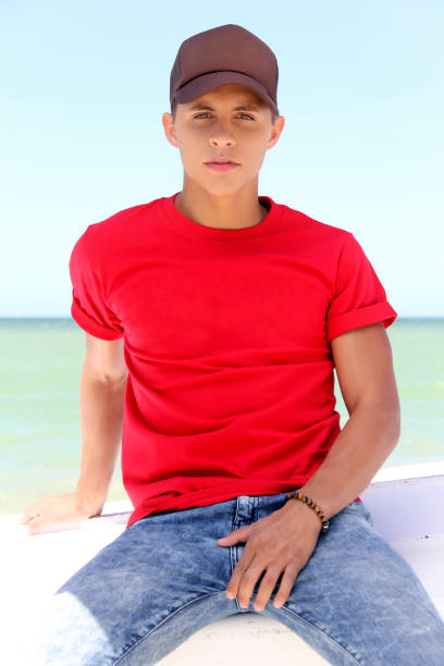 istock young man with red t-shirt and brown cap, on the beach. 1626207665