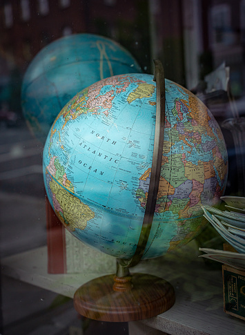 Antique globes of the Earth sit in a dusty shop store window. Small town in Massachusetts.