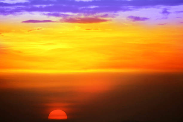 sunset colorful purple yelllow orange sky and dark cloud and sun lower left flame