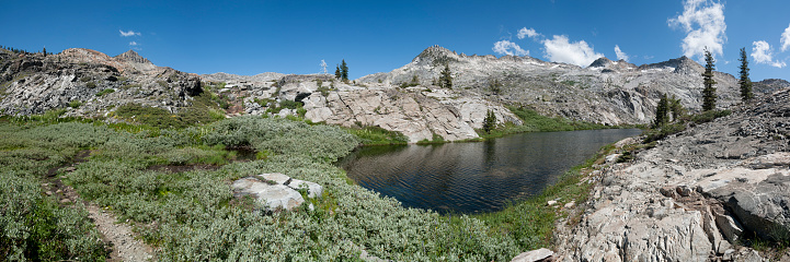 Hiking trail and unnamed lake between Twin Lakes and Island lake, east of Wrights lake, El Dorado National Forest, Sierra Nevada, California. Willow bushes and granite mountain slopes on a sunny summer day. Stitched panoramic image.