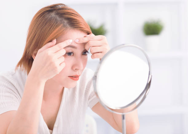 istock Young woman squeezing pimple spot for removing from face. 1626423914