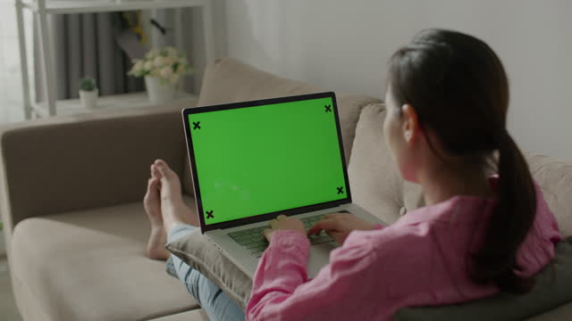 Woman using Laptop with green screen at home