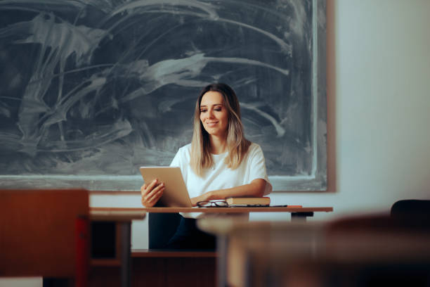 istock Happy Teacher Holding a Pc Tablet Sitting at the Desk 1626469674