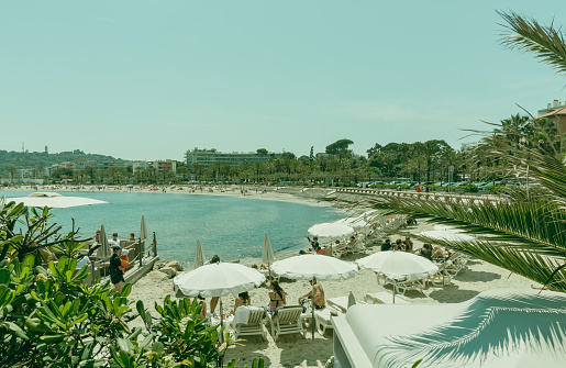 Antibes France - May 1 2023;  1960's style retro colours image of Mediterranean crowded beach, on French Riviera.