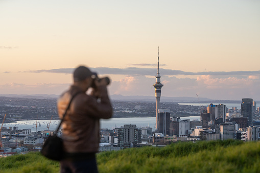 mature person on top of hill and taking photo of city