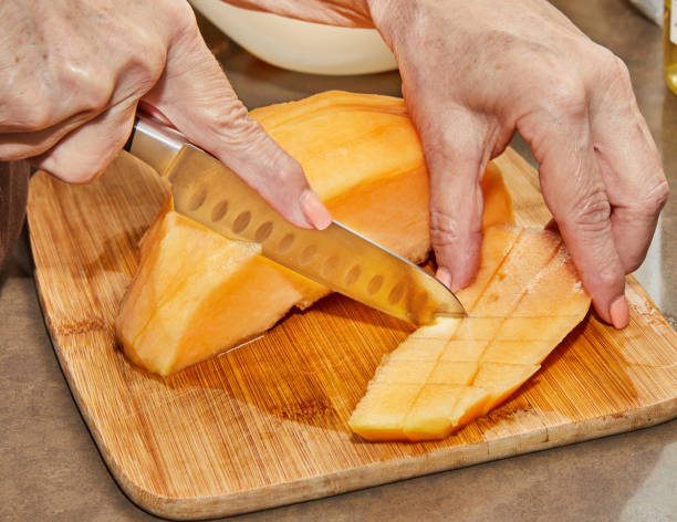 istock Chef cuts melon into cubes on wooden board in the kitchen 1626582618