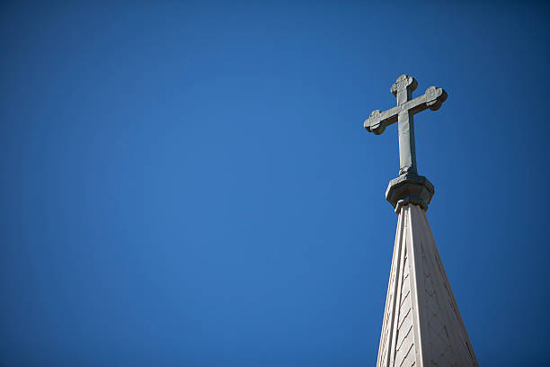 Church Steeple and Cross A Crucifix rises high above the skyline on top of a church's steeple. steeple stock pictures, royalty-free photos & images