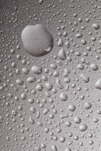 Macro silver water droplets on metal surface