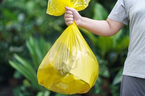 Man Volunteer charity holding garbage yellow bag and plastic bottle garbage for recycling cleaning.