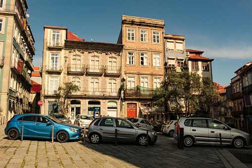 Facades with windows and balconies of old buildings, and parked cars in Campo dos Matirios da Patria, in the historic center of the city of Porto, Portugal, Europe