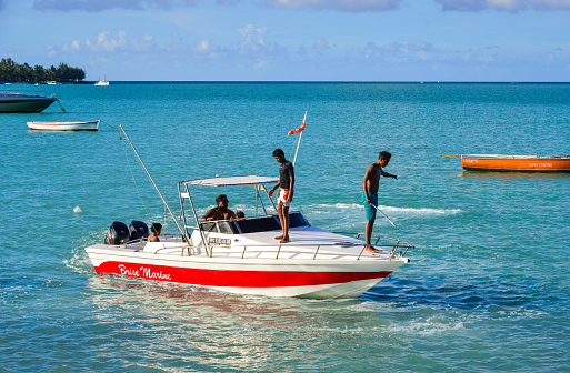 Grand Baie, Mauritius - Jan 9, 2017. People standing on a speedboat in Grand Baie, Mauritius Island. Mauritius is a major tourist destination, ranking 3rd in the region.