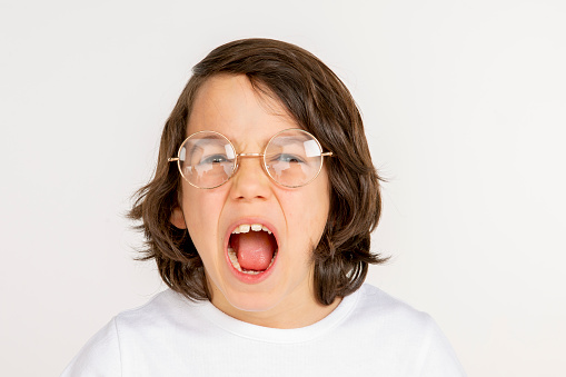 Portrait of a young boy. 10 year old boy make face on white background. White t-shirt and red sweatpants. white people.