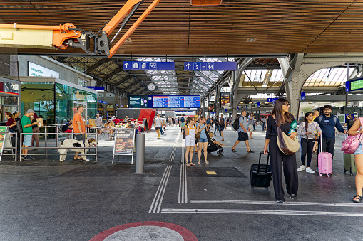 Crowd of people at railway main station at City of Zürich with blue departure board on a hot summer day. Photo taken August 19th, 2023, Zurich, Switzerland.