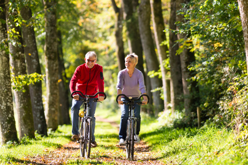 Senior Man and woman exercising with bicycles outdoors, they are a couple