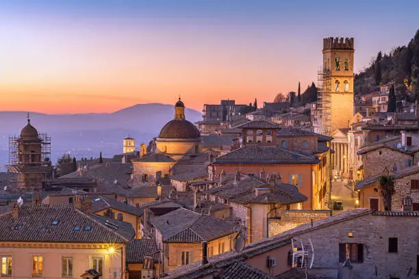 Assisi, Italy rooftop hilltop old town skyline at dusk.