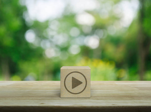 Business music online concept Play button icon on wood block cube on wooden table over blur green tree in park, Business music online concept download festival stock pictures, royalty-free photos & images