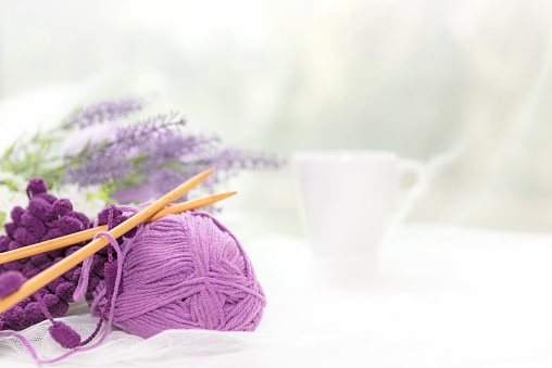Close up purple crochet.  Coffee morning.  White  steaming cup of hot coffee for relax after working hobbies crochet on white wooden near window with flowers, cup coffee white background