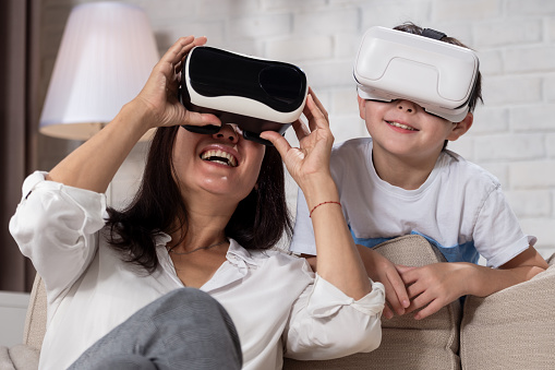 Mother and son using VR glasses in living room