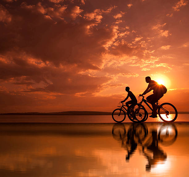 istock two mountain biker silhouette in sunrise with reflection 162672474