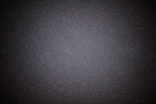 Overhead shot of a black sand texture background with spotlight.