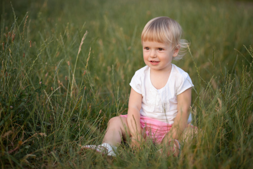 baby girl sitting in grass smiling