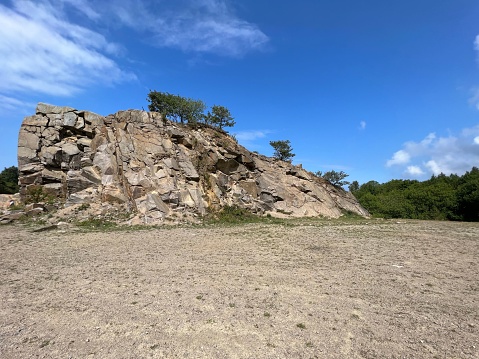A large rock in a deserted and uncultivated area against a cloudy blue sky