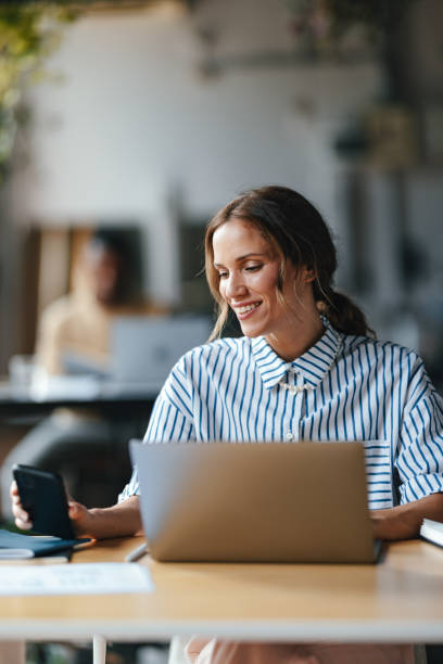 istock A Happy Beautiful Blonde Businesswoman Holding Her Mobile Phone While Working On Her Computer 1626847864