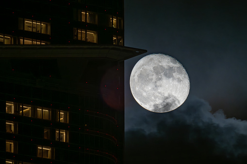 The full moon rises over the City of London skyline, UK