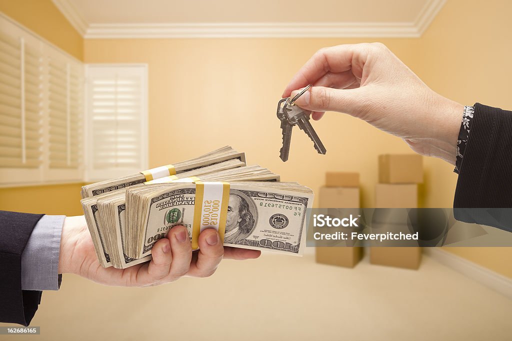 Handing Over Cash For House Keys man and Woman Handing Over Cash For House Keys Inside Empty Room with Boxes. Abundance Stock Photo