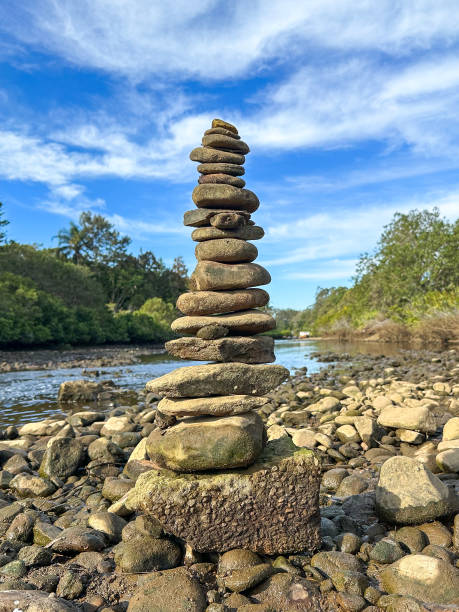 istock Rock stack Cairn built on the river bank edge.  Rocks in the front.  River water, greenery in the background. Blue skies in the distance. Gold Coast Queensland Australia 1626869050