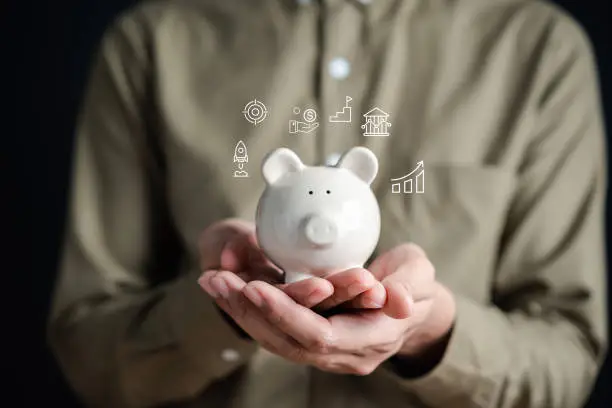 Photo of Businessman saving money in piggy bank goal achievement. Funds and stock Investment profits. assets, wealth, lucrative. Purchase insurance and investing for retirement concept.