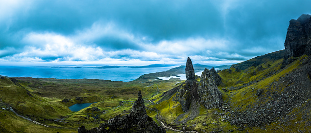 A misty, atmospheric, rocky landscape with golden sunrise light at the iconic rock pinnacle Old Man of Storr on the Isle of Skye in the Scottish Highlands.