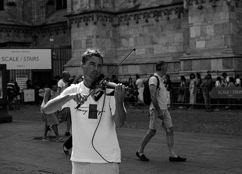 MILAN, ITALY - August 12, 2023: street artist plays violin under the cathedral of milan