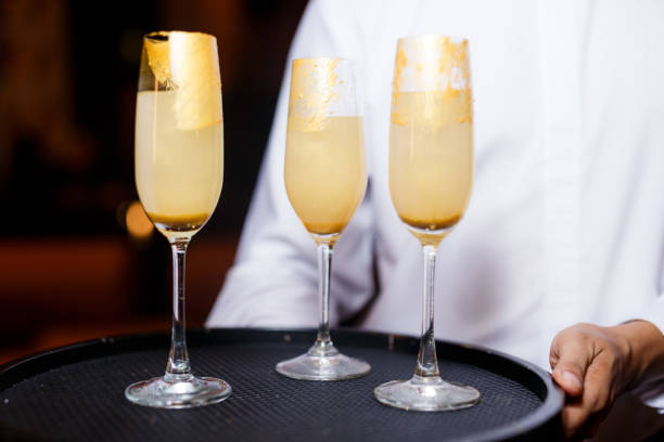 istock Server Holding Flutes of Golden Cocktail Drinks 1626965196