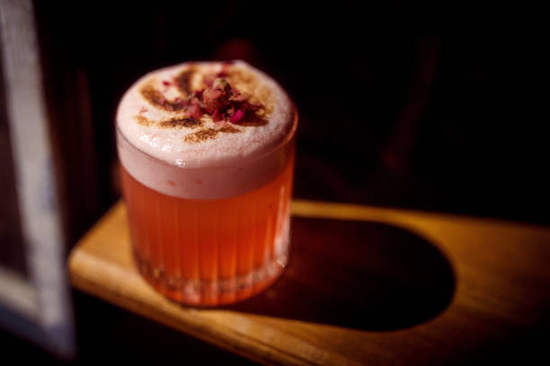 Short Glass Red Cocktail With Dried Flower Garnish torched Whipped Cream on top stock photo