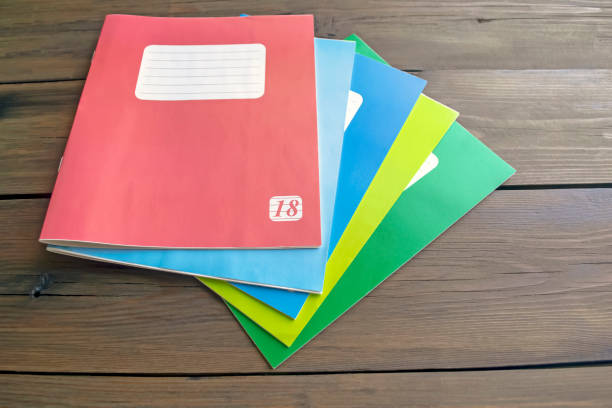 istock Colored notebooks for school. On a wooden table are several thin notebooks for school. 1627009719