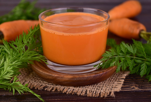 A glass of fresh carrot juice on a wooden tray.Close-up.