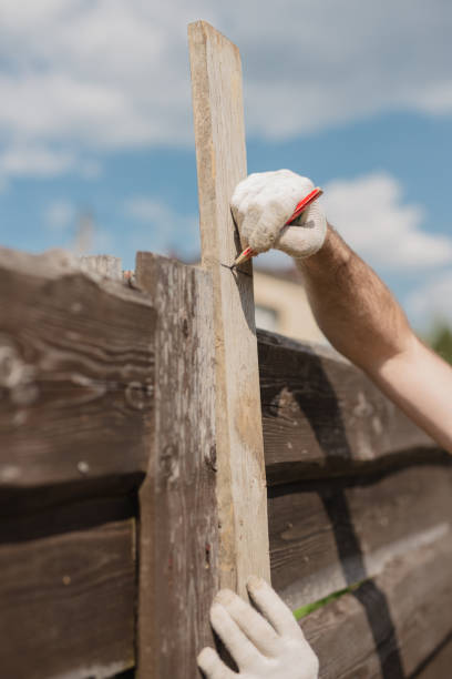 istock A man builds and paints a fence from rough boards 1627040394