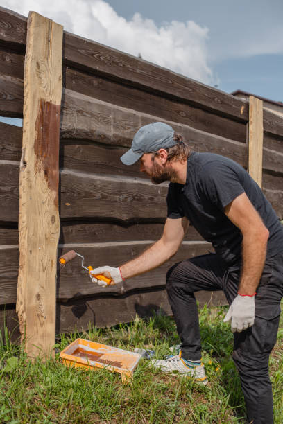 istock Man applying protective coat to wooden fence slats 1627040607