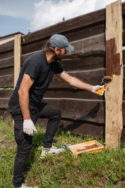 istock A man builds and paints a fence from rough boards 1627040935