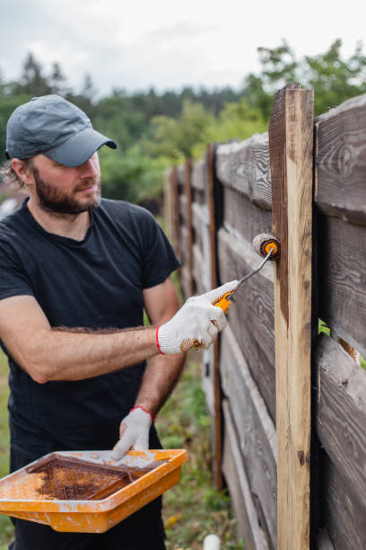 istock A man builds and paints a fence from rough boards 1627041545