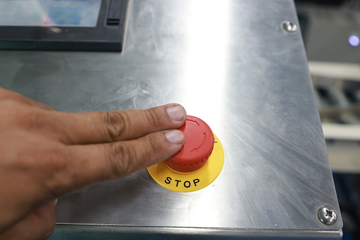 Stop the Red Button and the Hand of the Worker About to Press it. emergency stop button.  stop button for manual pressing.