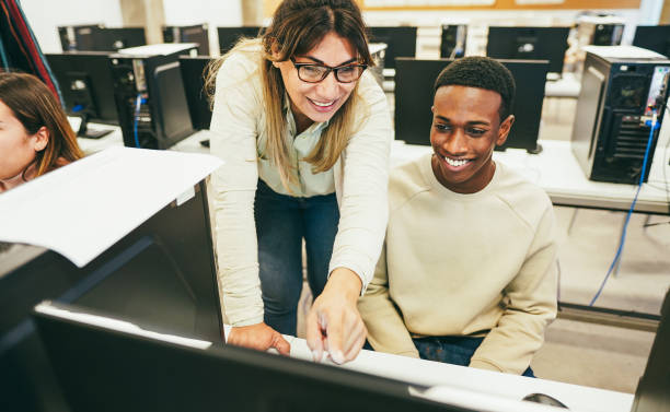 istock Young student learning how to use personal computer with his teacher at IT college class - Back to school and campus lifestyle concept - Main focus on female face 1627071876