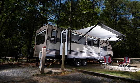 Both awnings fully extended on a camper trailer at a forested campsite