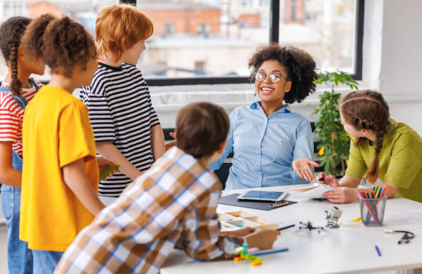 istock African american teacher smiling and helps students during lesson in bright classroom 1627104075