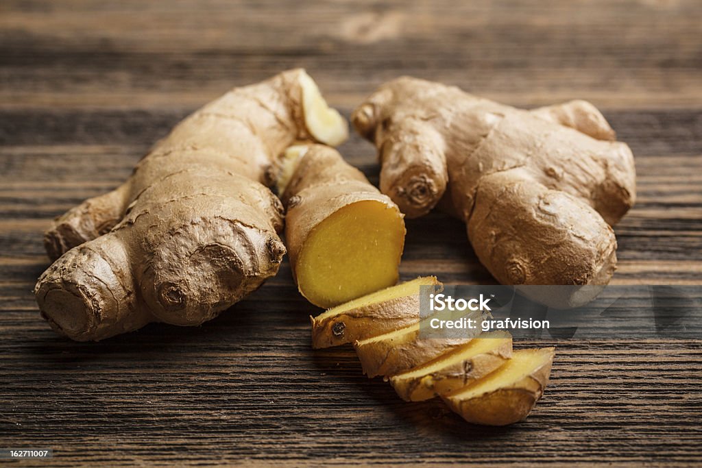 Fresh ginger whole and chopped on rustic wood surface Fresh ginger, whole and sliced on rustic wooden background Ginger - Spice Stock Photo