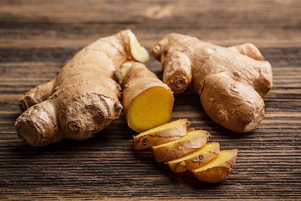 Fresh ginger whole and chopped on rustic wood surface stock photo