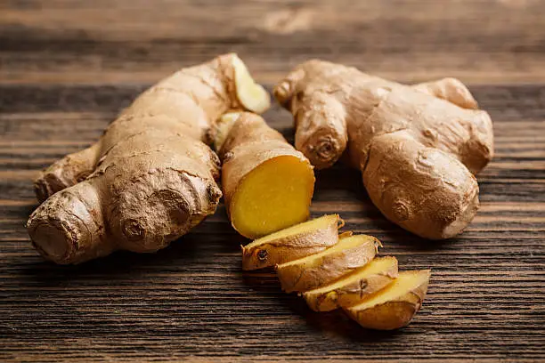 Photo of Fresh ginger whole and chopped on rustic wood surface