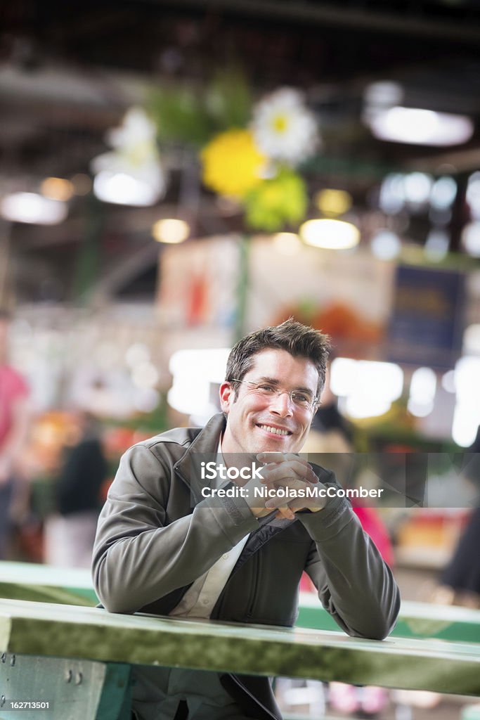 Feliz sorridente homem sentado no farmer's market vertical - Foto de stock de 30 Anos royalty-free